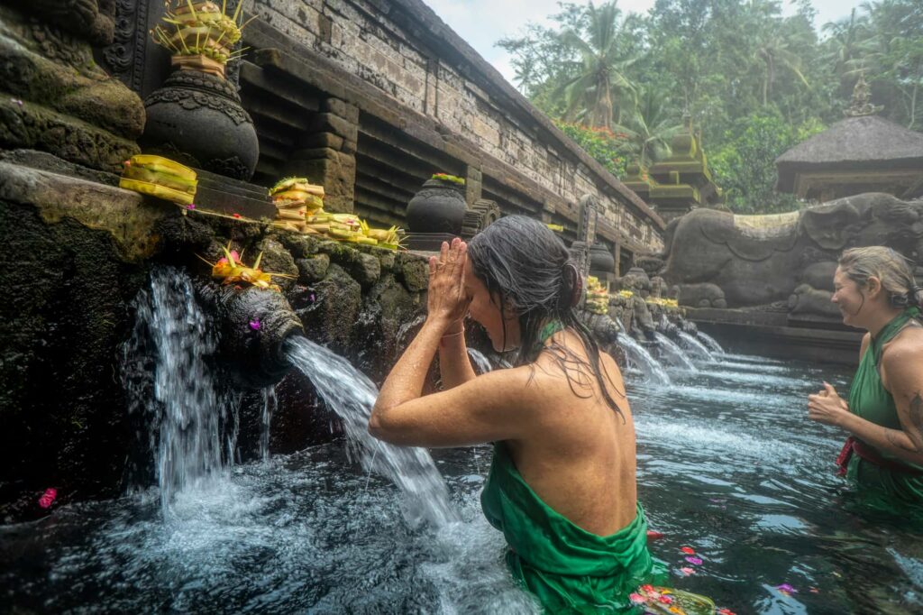Eine Frau wäscht sich im Tempel in Bali